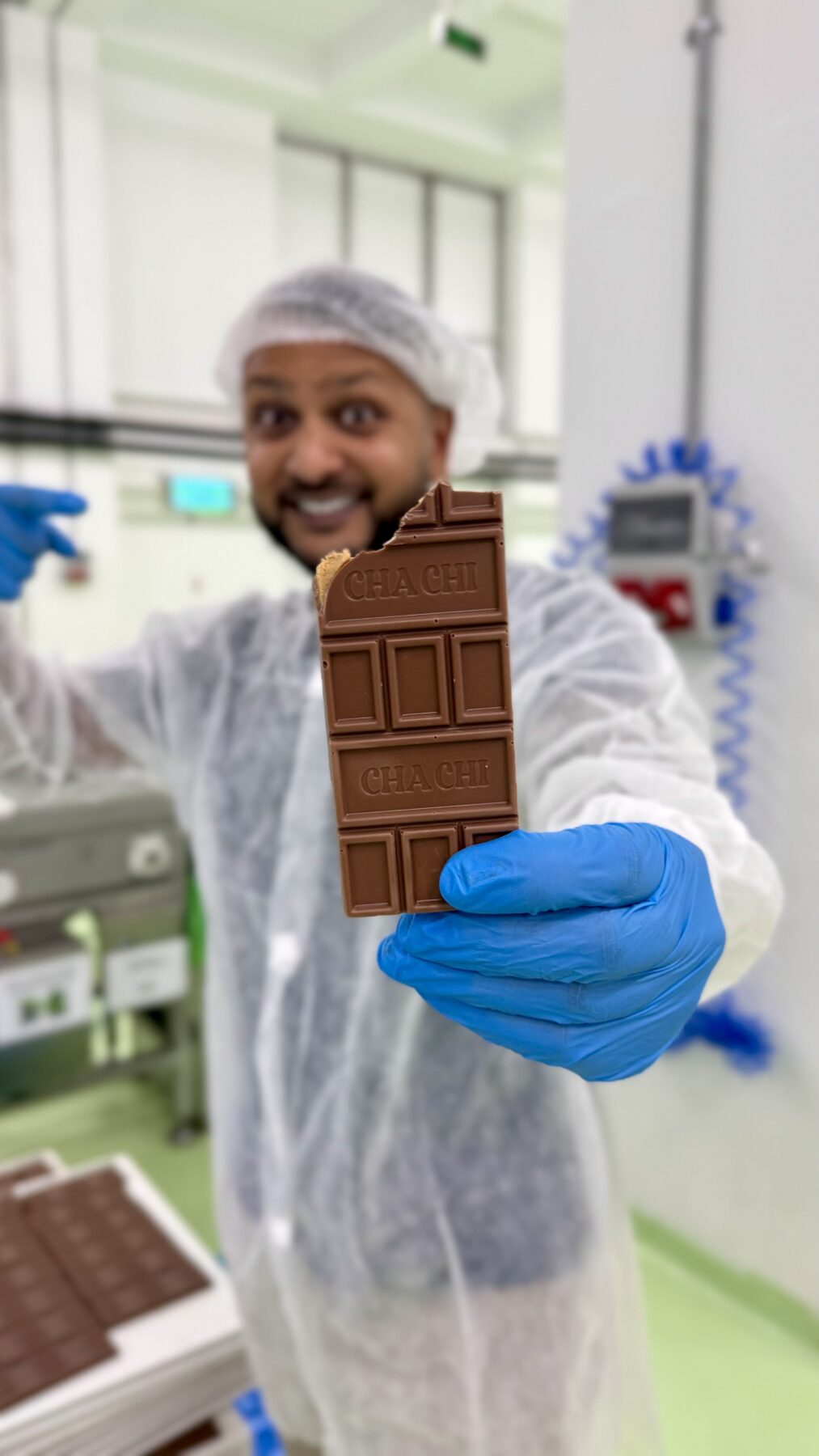 Cha Chi Versaci houdt een aangebroken chocoladereep omhoog met CHA CHI in de chocolade gedrukt.